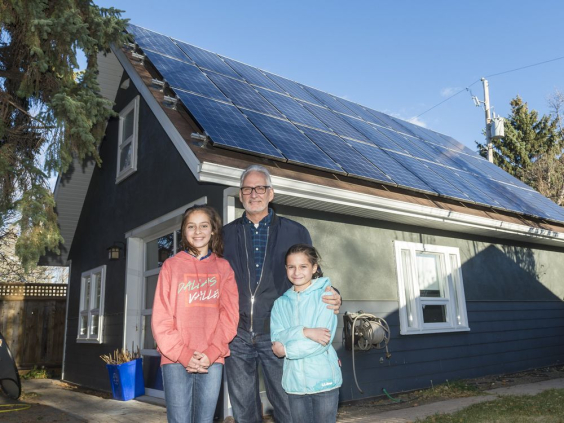Stephen Hall stands with his daughters Amelia, left, and Penelope, right, in front of solar panels mounted on his home studio. MICHAEL BELL / Regina Leader-Post